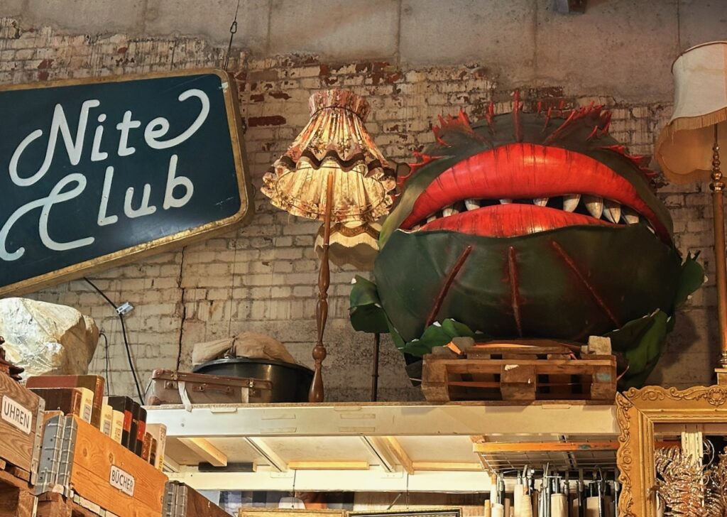 Regal im gemeinnützigen Fundus für ausrangierte Requisiten und Bühnenbilder im Oberhafen Hamburg, mit Requisit Audrey, der fleischfressenden Pflanze aus dem Musical Little Shop of Horrors.